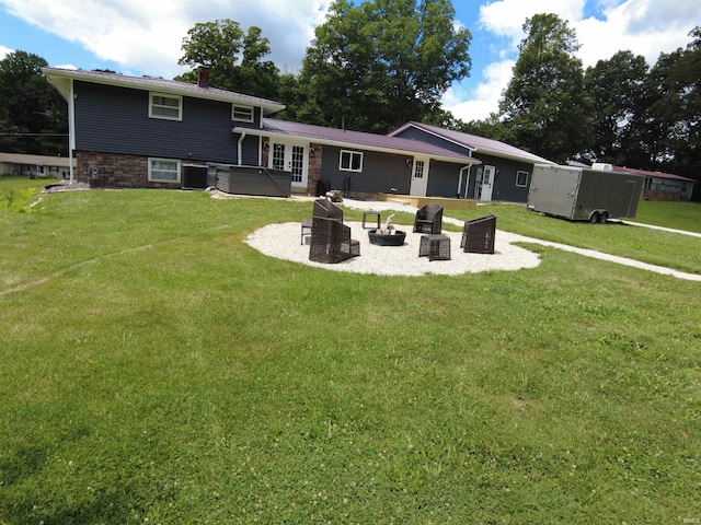 back of property with a patio, a lawn, central air condition unit, a jacuzzi, and an outdoor fire pit