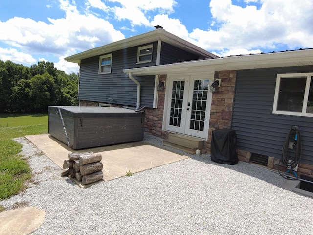 back of property with a hot tub, a patio area, and french doors