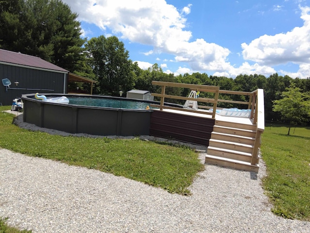 view of swimming pool featuring a yard, a deck, and a storage shed