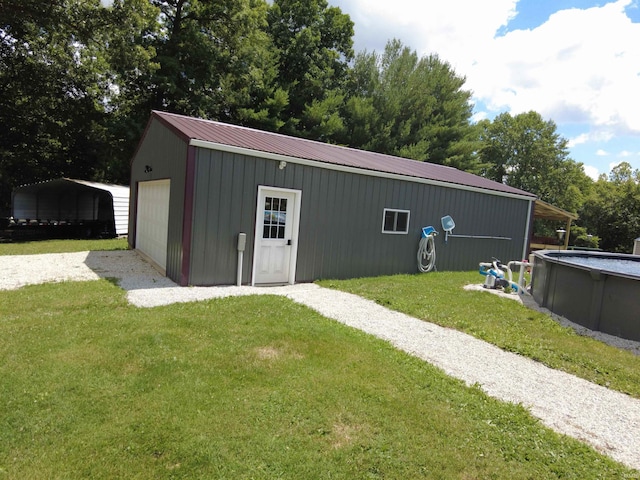 view of outbuilding featuring a yard, a garage, and a carport