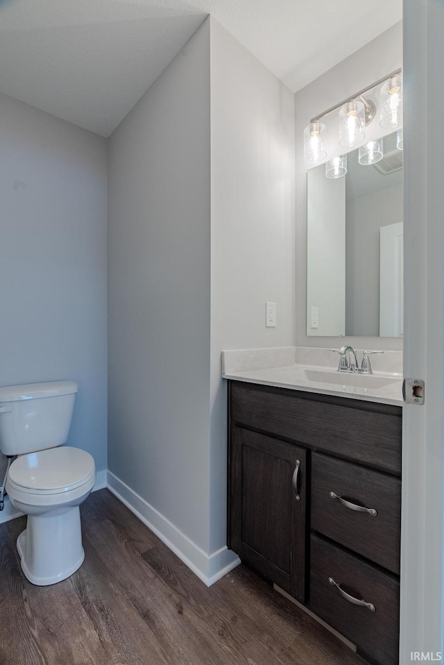 bathroom with baseboards, wood finished floors, toilet, and vanity