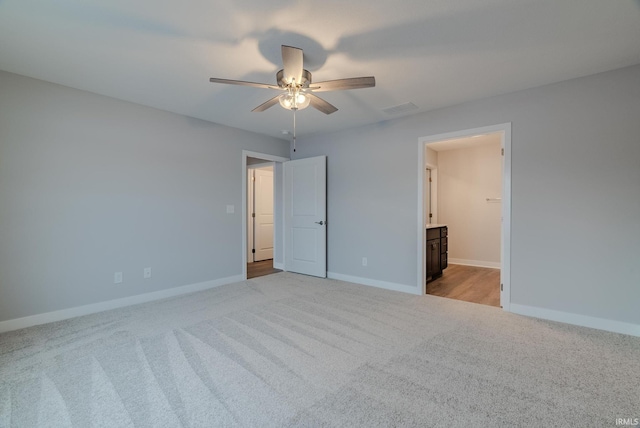 unfurnished bedroom featuring ensuite bath, ceiling fan, and light colored carpet