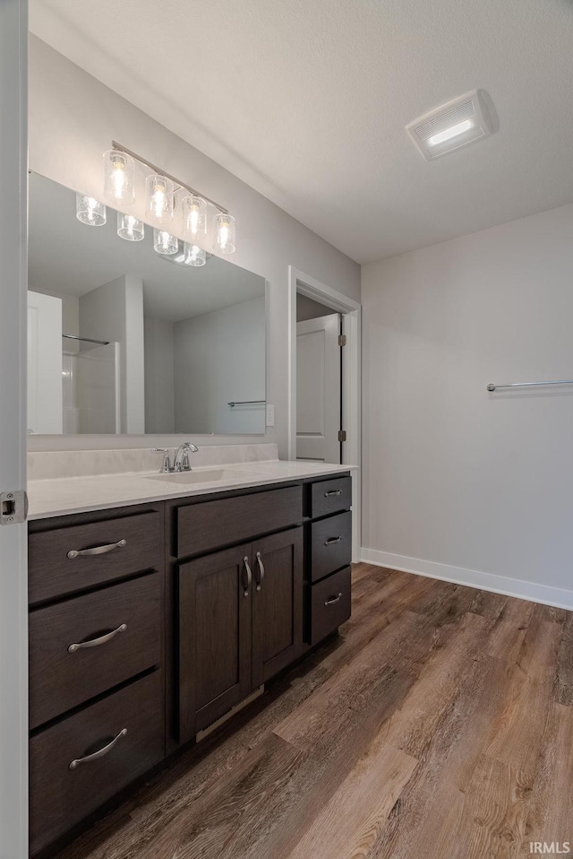 bathroom with hardwood / wood-style floors, vanity, a textured ceiling, and walk in shower