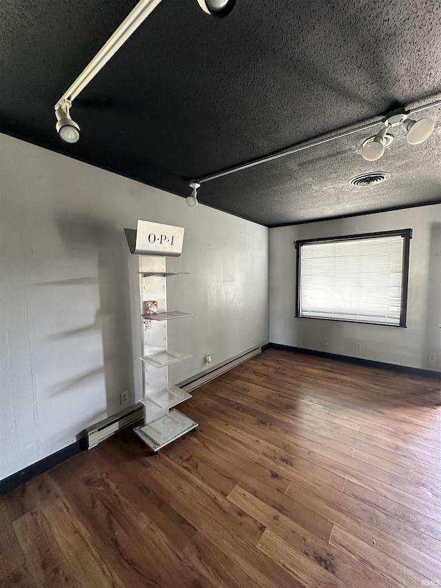 spare room with a textured ceiling, dark wood-type flooring, and a baseboard radiator