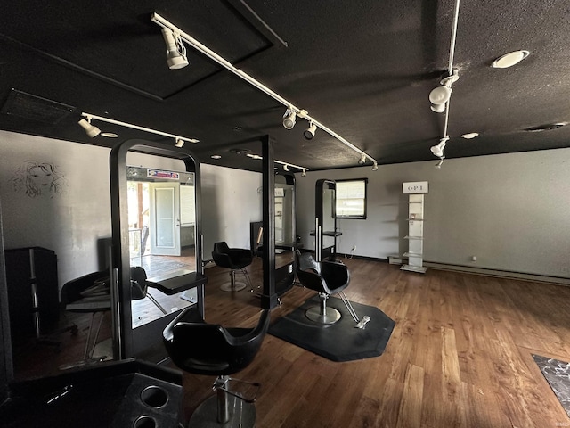 exercise room featuring hardwood / wood-style floors, a textured ceiling, and rail lighting