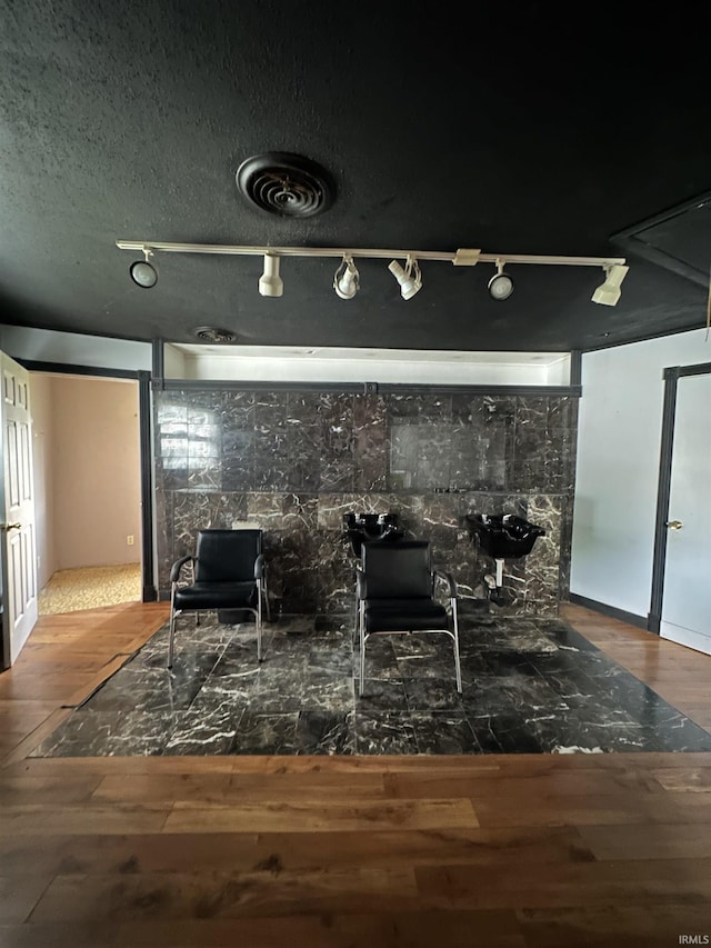 living area featuring a textured ceiling, rail lighting, and hardwood / wood-style flooring