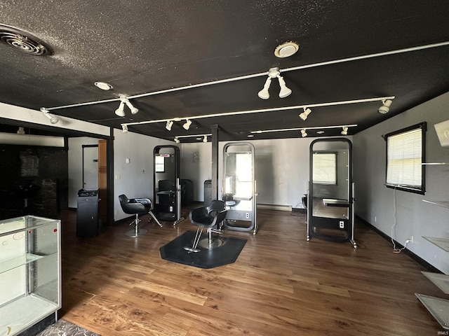 workout area with track lighting, dark wood-type flooring, and a textured ceiling