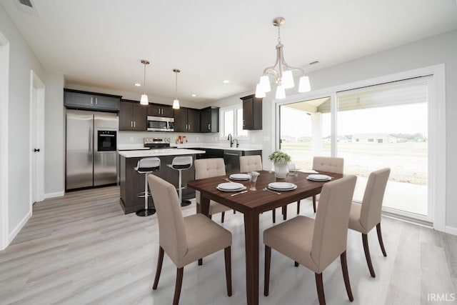 dining room with a notable chandelier, light hardwood / wood-style flooring, and sink