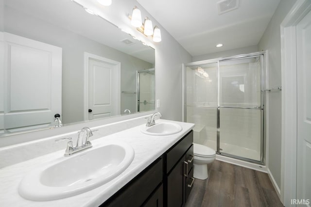 bathroom featuring wood-type flooring, toilet, a shower with door, and vanity