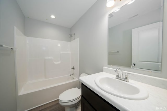 full bathroom with bathing tub / shower combination, hardwood / wood-style floors, vanity, and toilet