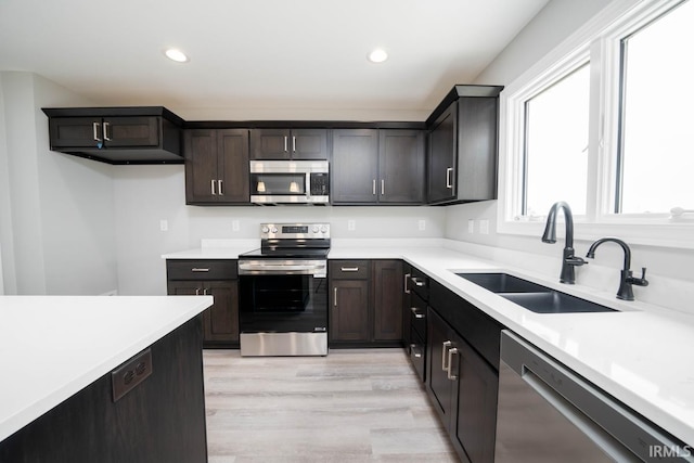 kitchen featuring appliances with stainless steel finishes, light hardwood / wood-style floors, sink, and dark brown cabinets