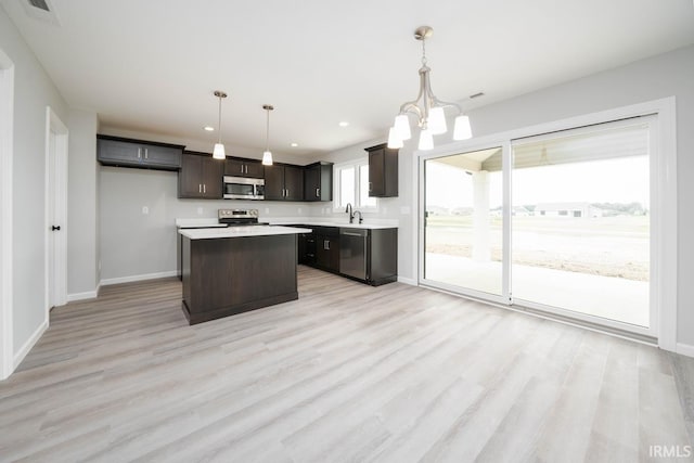 kitchen featuring sink, a chandelier, hanging light fixtures, appliances with stainless steel finishes, and light hardwood / wood-style floors