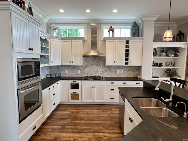 kitchen with sink, wall chimney exhaust hood, appliances with stainless steel finishes, decorative light fixtures, and white cabinetry