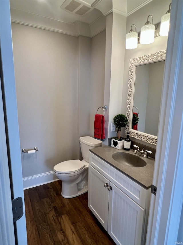 bathroom featuring wood-type flooring, vanity, toilet, and ornamental molding