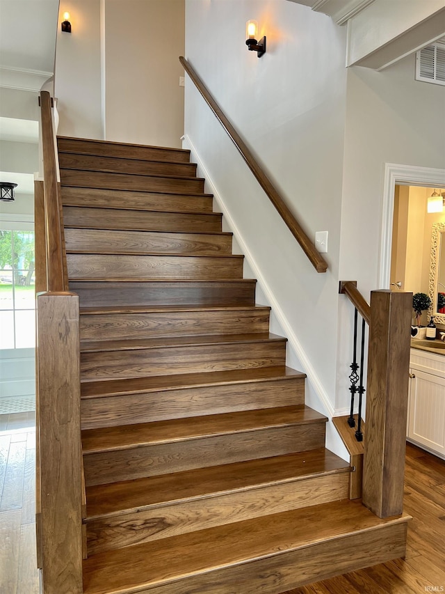 stairway with hardwood / wood-style floors and crown molding