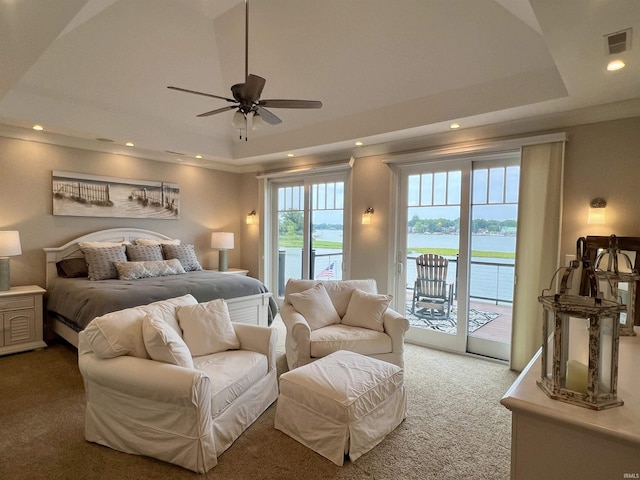 carpeted bedroom with access to outside, a raised ceiling, ceiling fan, and a water view