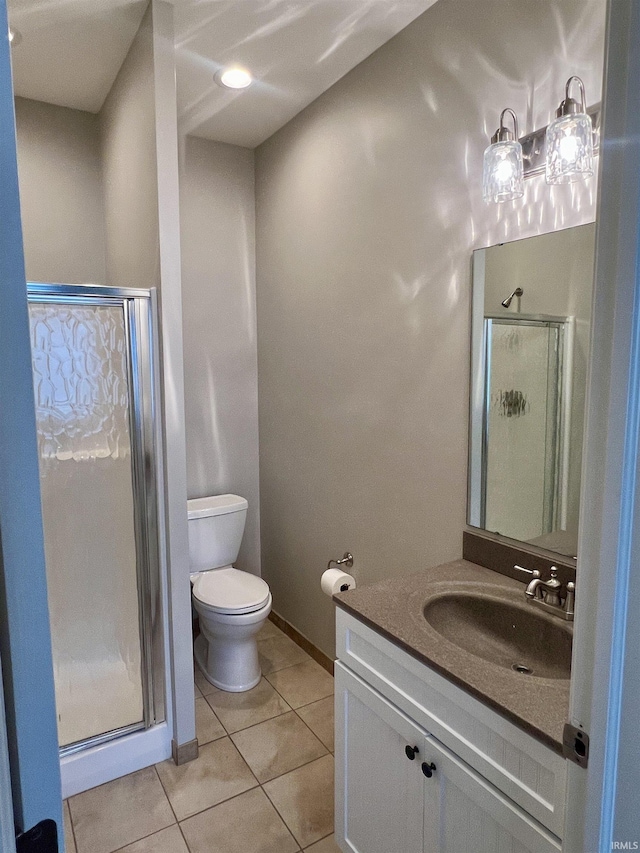 bathroom with tile patterned flooring, vanity, toilet, and a shower with shower door