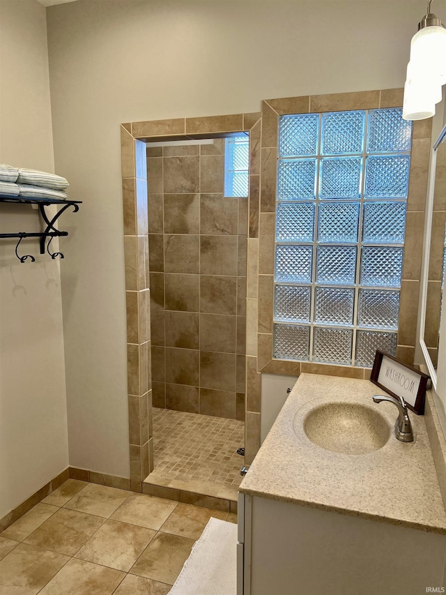 bathroom with tile patterned floors, vanity, and a tile shower