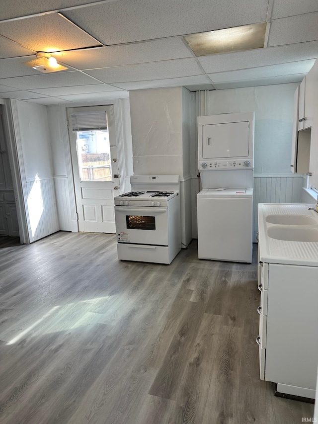 kitchen featuring sink, stacked washing maching and dryer, dark wood-type flooring, white range with gas stovetop, and a paneled ceiling