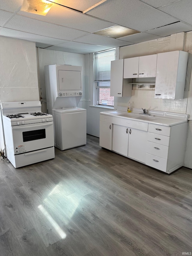 kitchen featuring a drop ceiling, white cabinets, sink, stacked washer and dryer, and white range with gas cooktop