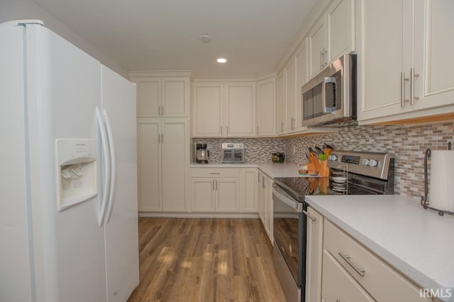 kitchen featuring light hardwood / wood-style flooring, decorative backsplash, white cabinetry, and stainless steel appliances