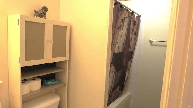 bathroom featuring toilet and shower / tub combo with curtain