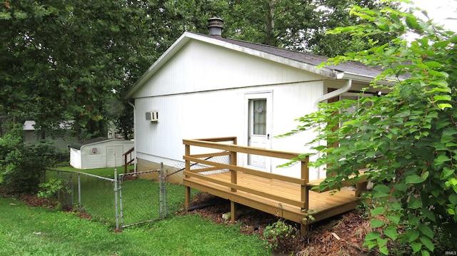 exterior space with a storage unit, a lawn, a wooden deck, and a wall mounted AC