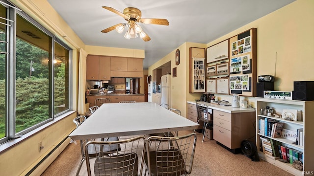 kitchen with ceiling fan, white fridge, a breakfast bar area, and a baseboard radiator