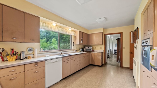 kitchen featuring light brown cabinets, white dishwasher, oven, and sink