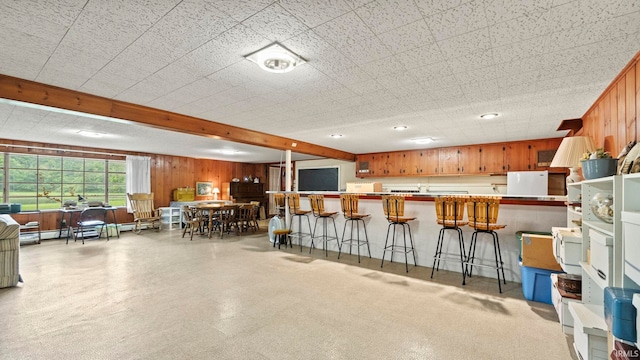 bar with white fridge, beam ceiling, wooden walls, and a baseboard heating unit