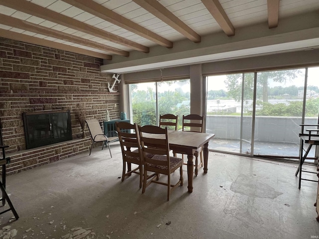 dining area featuring a fireplace, beam ceiling, and a wealth of natural light