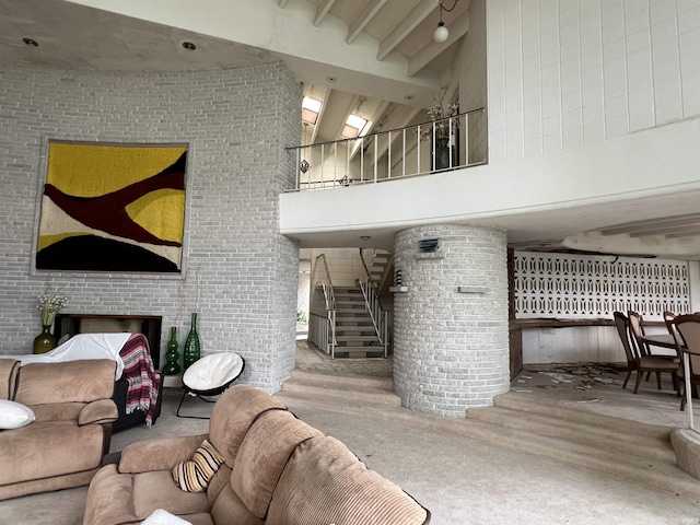 living room featuring a high ceiling, concrete floors, a brick fireplace, and brick wall