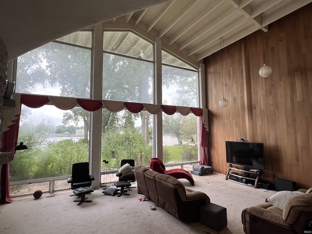 carpeted living room with a wealth of natural light, wooden walls, and vaulted ceiling