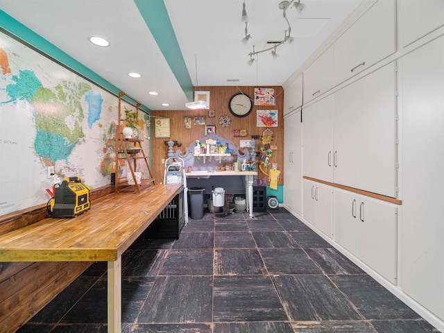 interior space with white cabinetry, hanging light fixtures, and wooden walls