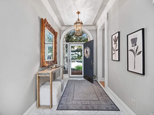 foyer with crown molding and an inviting chandelier