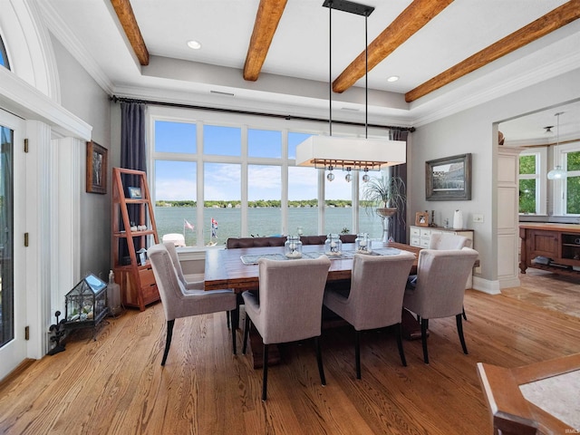 dining area with beamed ceiling, light wood-type flooring, a water view, and crown molding