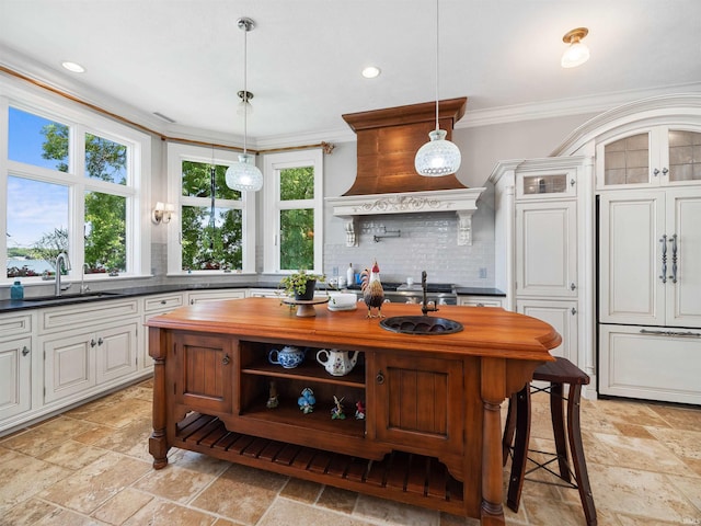 kitchen with pendant lighting, tasteful backsplash, white cabinetry, and crown molding