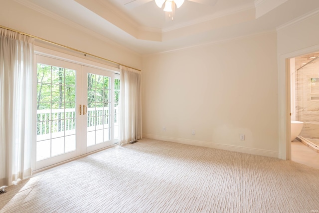 carpeted spare room with a raised ceiling, french doors, ornamental molding, and ceiling fan