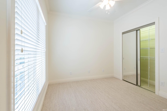 unfurnished bedroom featuring light carpet, a closet, ceiling fan, and crown molding