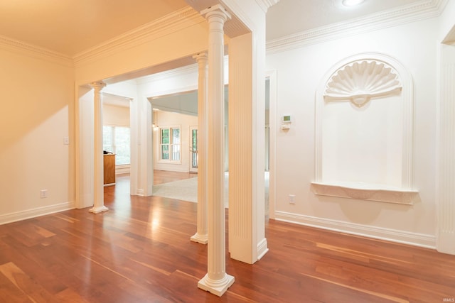 hallway featuring dark wood-type flooring, crown molding, and ornate columns