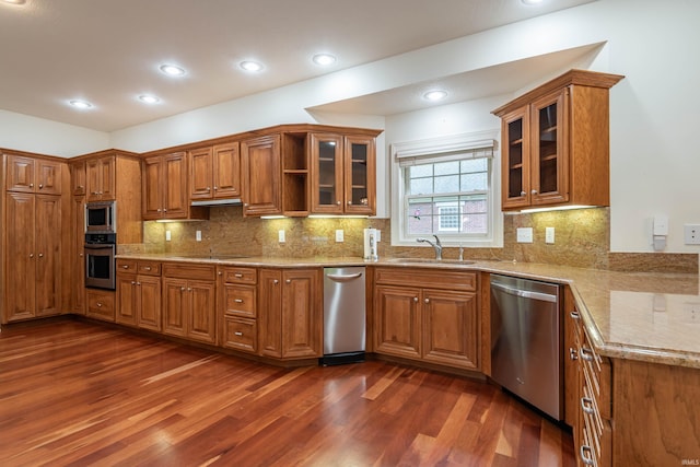 kitchen with stainless steel appliances, dark hardwood / wood-style flooring, light stone counters, and sink