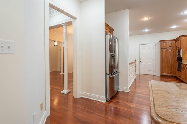 corridor with dark hardwood / wood-style flooring and decorative columns