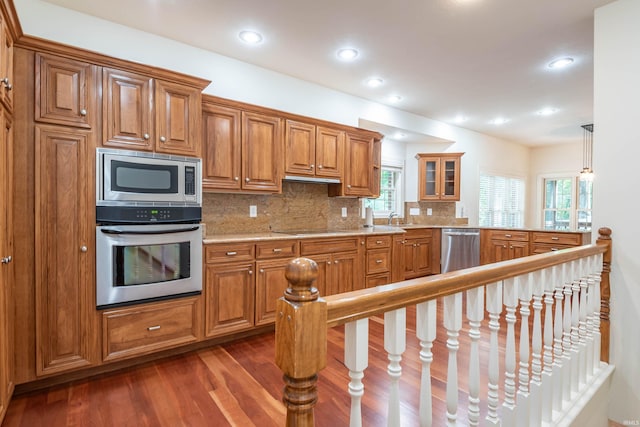 kitchen with stainless steel appliances, backsplash, a wealth of natural light, and dark wood-type flooring