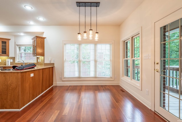 kitchen with dark hardwood / wood-style floors, tasteful backsplash, and decorative light fixtures