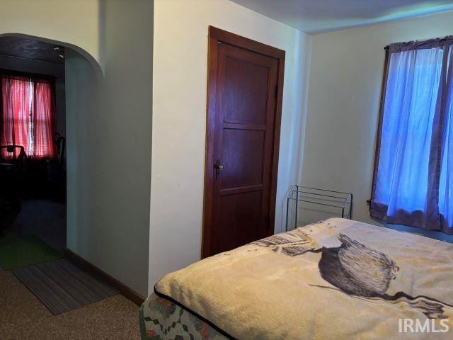 bedroom featuring arched walkways, carpet, and baseboards