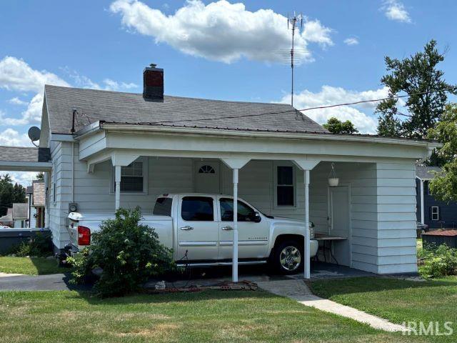 bungalow-style home featuring a carport and a front yard