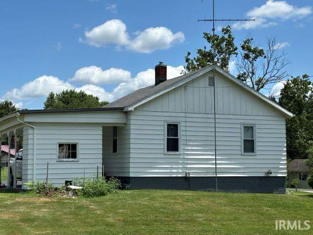 rear view of property featuring a chimney and a yard