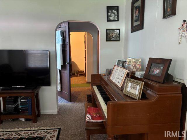 carpeted living area featuring baseboards and arched walkways