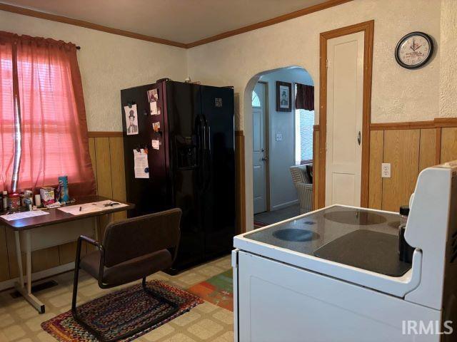 kitchen featuring range, black refrigerator with ice dispenser, and ornamental molding