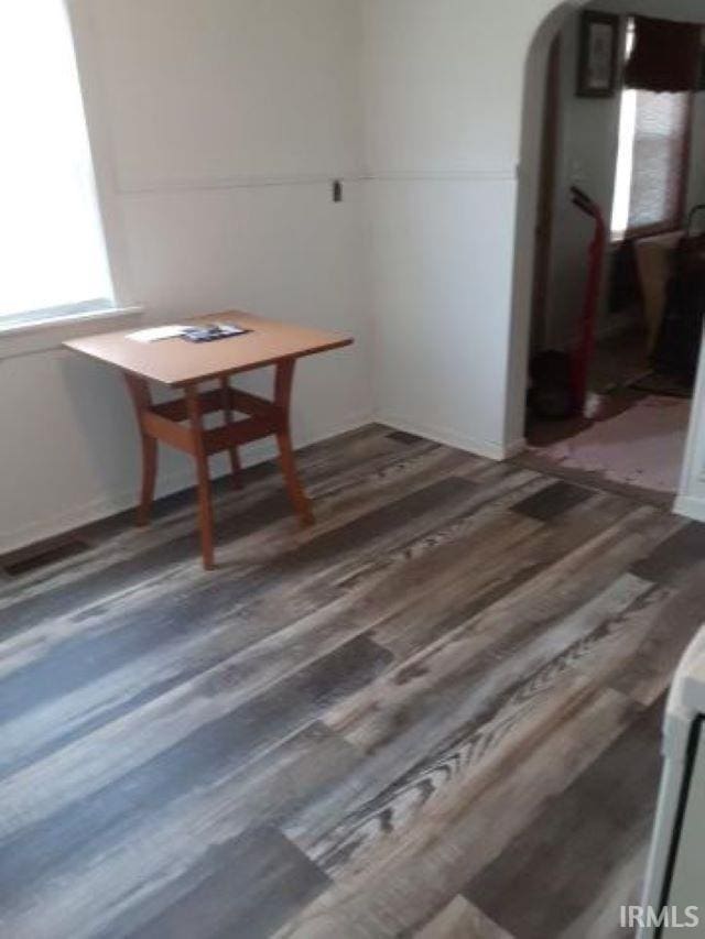 unfurnished dining area with arched walkways, wood finished floors, and visible vents